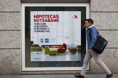 Un caminante cruza delante de un banco en Madrid. LUIS TEJIDO