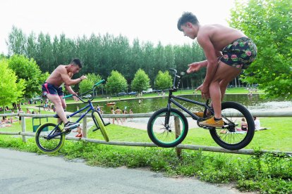 Dos jóvenes vuelan con sus bicicletas junto a la playa fluvial de Villoria de Órbigo. DL