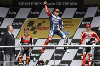 El rey Juan Carlos observa al piloto Jorge Lorenzo, que celebra en el podio la victoria conseguida.