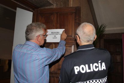 Julio Cayón, colocando ayer el papel del Registro junto a un policía.