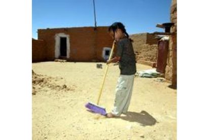 Una niña barre el patio de su casa