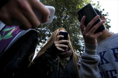 Un grupo de adolescentes utilizan sus teléfonos móviles.