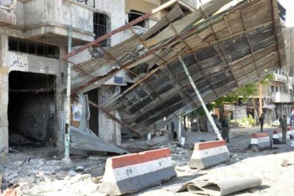 Soldados del Ejército sirio inspeccionan el daño causado por un coche bomba en la ciudad de Homs, en el centro de Siria, el lunes por la mañana.