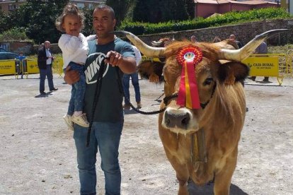 El joven ganadero, con su hija en brazos, junto a una de sus vacas en un reciente concurso. ARAUJO