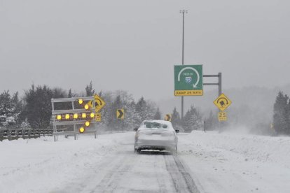 Un vehículo se aproxima a una curva sobre la calzada nevada en Dedham, Massachussets.