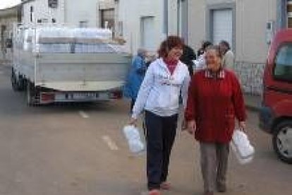 Vecinos de Nistal recibiendo agua en garrafas en una foto de archivo