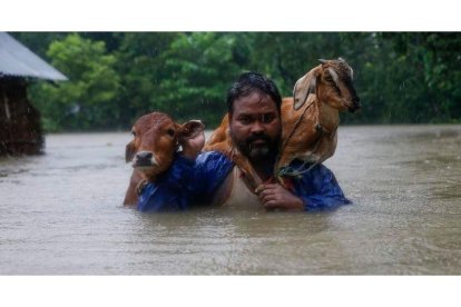 Un hombre carga a hombros con sus animales para que no mueran ahogados por las inundaciones. NARENDRA SHRESTHA