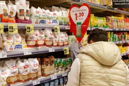 Una mujer escoje artículos marcados con su precio en un supermercado.