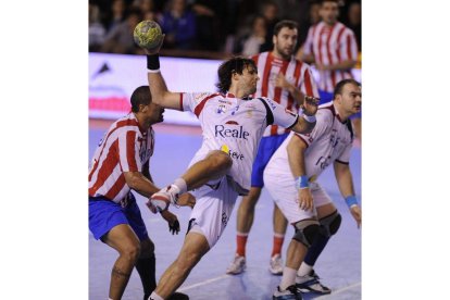 El pivote argentino Gonzalo Carou consigue zafarse del duro marcaje de ‘La Roca’ Dinart y lanzar a portería del Atlético de Madrid.