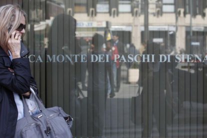 Una mujer pasa ante una oficina del banco Monte Dei Paschi Di Siena en Roma.