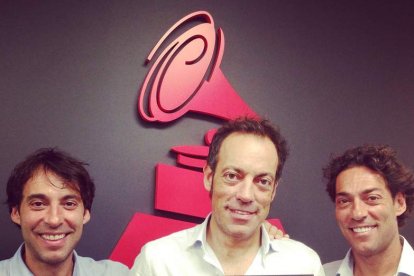 Los leoneses Raúl, Manolo y Óscar Quijano posan ante un cartel con la conocida estatuilla de los Grammy Latino