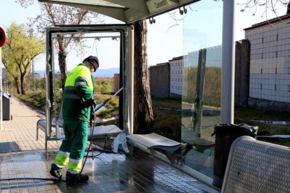 Un operario limpia la parada de autobús en la que un vehículo ha chocado en Sabadell.