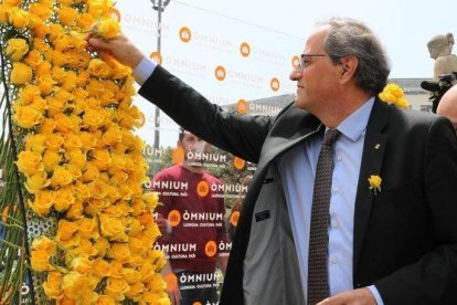 El presidente Quim Torra coloca una rosa amarilla en el mural de Òmnium.