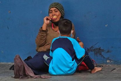 Una y un niño permanecen sentados en una calle en la que piden diner este miércoles en Tegucigalpa (Honduras). GUSTAVO AMADOR