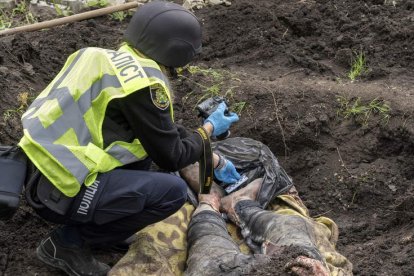 Imagen de un soldado ucraniano fotografiando el cadáver de un civil en Jarkov. VASILIY ZHLOBSKY