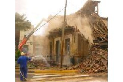 Un obrero arroja agua con una manguera durante la demolición