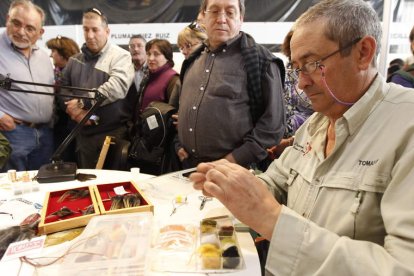 Un artesano hace una demostración en directo del montaje de una pluma.