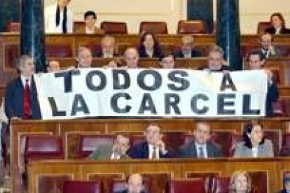 Los diputados de IU mostraron un cártel con la leyenda «Todos a la cárcel» durante la votación