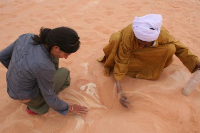 La arqueóloga ponferradina Mireya González escarba en la arena del desierto junto a un nativo, en un imagen tomada en las dunas del suroeste de Libia y anterior a la revuelta popular contra el sátrapa Muamar el Gadafi.