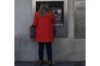 Una mujer ante un cajero de banco.