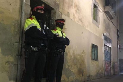 Dos mossos ante el portal de la calle de la Riera Alta donde se ha cometido el crimen.