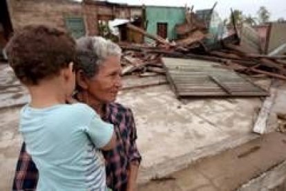 Una mujer cubana, sosteniendo a su nieto, contempla los destrozos que ha causado el huracán