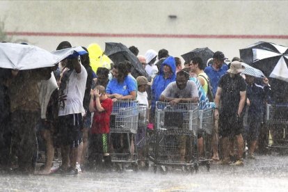 Un grupo de personas hace cola bajo una intensa lluvia en una tienda de ultramarinos en Carolina del Norte.