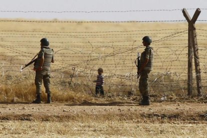 Un niño sirio espera tras las vallas de la frontera para cruzar hacia Turquía cerca de Akcacale (sureste), en el 2015.