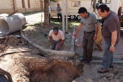 El alcalde (en medio), durante las labores para cubrir el agujero que se produjo en la calzada.