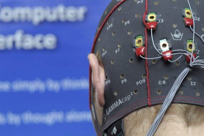 Un joven lleva un gorro con electrodos mientras juega a un videojuego.