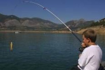 Un niño se inicia en el deporte de la pesca en las orilla del embalse de Los Barrios de Luna