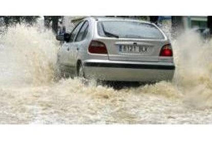 Un automovilista atraviesa una gran balsa de agua en una calle del barrio de Los Remedios