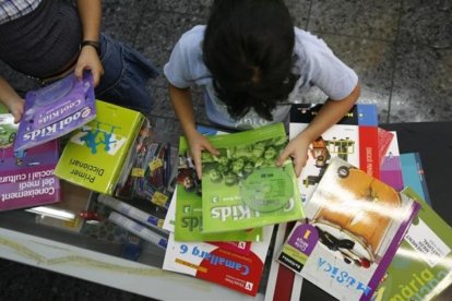 Dos niñas revisan unos libros de texto depositados sobre una mesa.