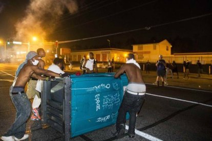 Manifestantes con un contenedor de basura.