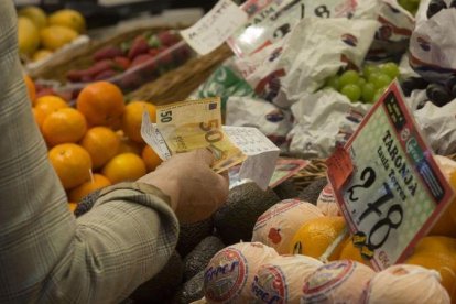 Una mujer paga por la compra de unos alimentos en un mercado.