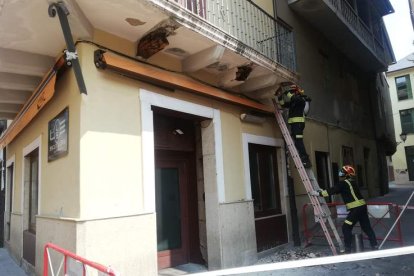 Dos bomberos retiran cascotes del balcón afectado en la calle del Reloj de Ponferrada. M. C.