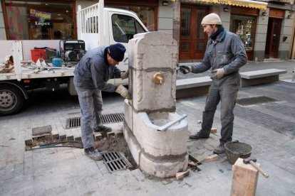 Dos operarios, colocando de nuevo la fuente en la rinconada del Conde.