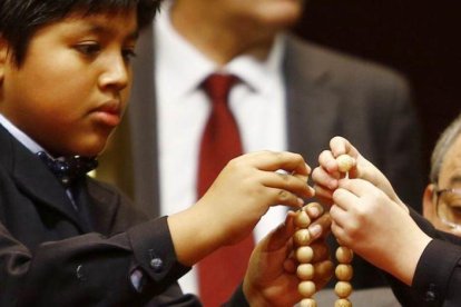 Dos niños ensartan las bolas de los números premiados de la Lotería de Navidad 2016.