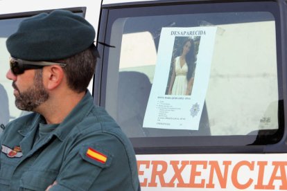 Un efectivo de la Guardia Civil junto al cartel de la joven. XOÁN REY