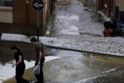 Dos jóvenes caminan por las calles de Sahagún minutos después de la impresionante tormenta