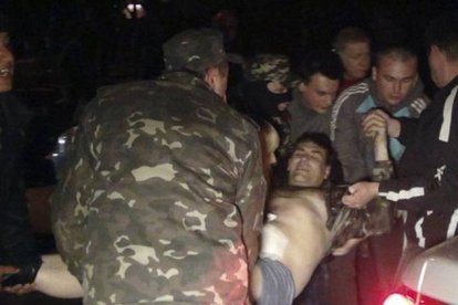 Un grupo de ciudadanos traslada a una persona herida durante el asalto de tropas prorrusas al cuartel de Mariupol, el miércoles por la noche.