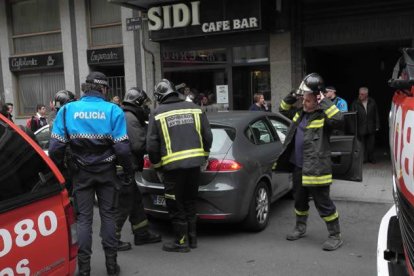 Bomberos y agentes de la Policía Local, junto al vehículo causante del suceso.