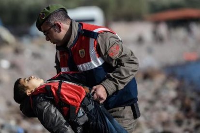 Un policía turco traslada el cuerpo sin vida de un niño tras otro naufragio en el Egeo.