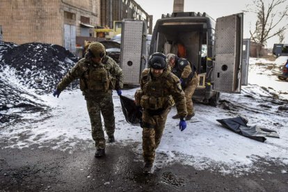 Miembros de la unidad de policía trasladan fallecidos durante un bombardeo. OLEG PETRASYUK