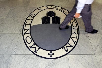 Un hombre camina sobre el logo del banco Monte Dei Paschi Di Siena en Roma.