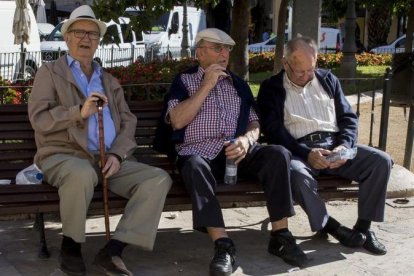 Tres jubilados descansan en un banco de un parque en Valencia.