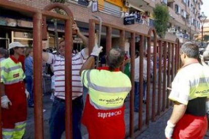 Varios operarios de Arganda del Rey comprueban una valla del recorrido del encierro.