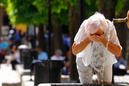 Una mujer se refresca en una fuente de  debido al calor sofocante más propio del mes de julio. SALAS