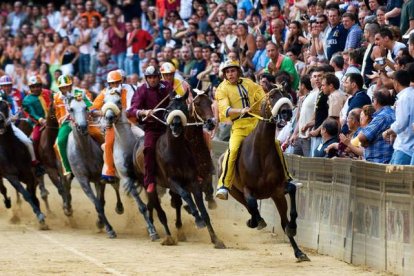 Varios competidores se disputan el Palio durante la carrera.