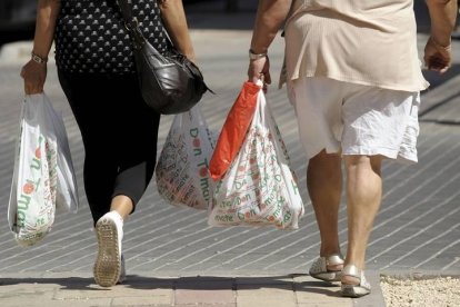 Dos mujeres llevan bolsas de plástico de la compra